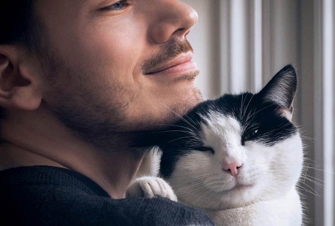 a-man-holding-black-and-white-cat