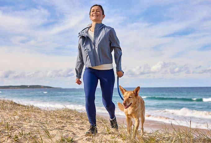 woman-walking-dog-on-sand-dunes-at-the-beach