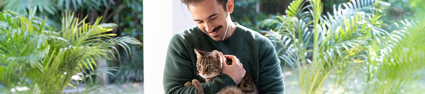 man-cuddling-cat-in-the-garden