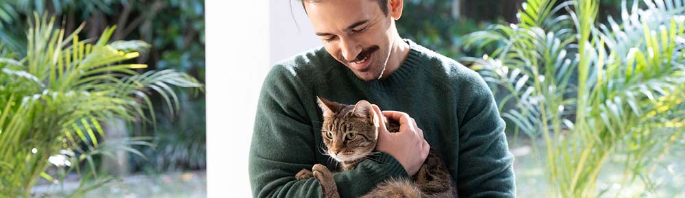 man-cuddling-cat-in-the-garden
