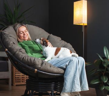 A-woman-seating-in-a-chair-with-a-small-dog-on-her-lap