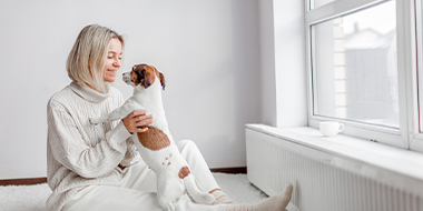 A-woman-is-playing-cushioned-with-a-small dog-on-her-lap
