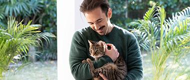 man-cuddling-cat-in-the-garden