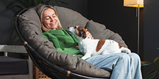 A-woman-seating-in-a-chair-with-a-small-dog-on-her-lap