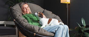 A-woman-seating-in-a-chair-with-a-small-dog-on-her-lap