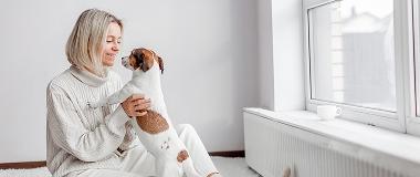 A-woman-is-playing-cushioned-with-a-small dog-on-her-lap